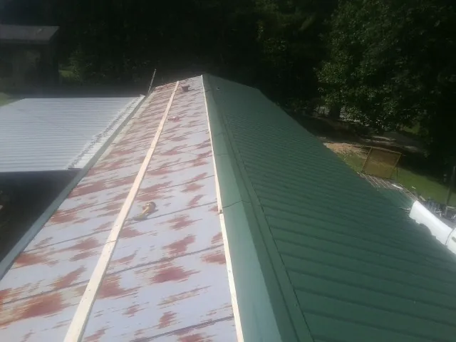 Old rusted panels beside newly installed green metal roofing — Wind Damage Roof Repair by Roofing Brothers in Elizabeth
