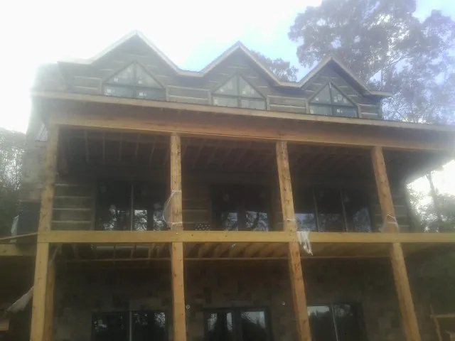 Dormers and porch framing on a large log home under construction — Roof Coating work by our crew in Elizabeth